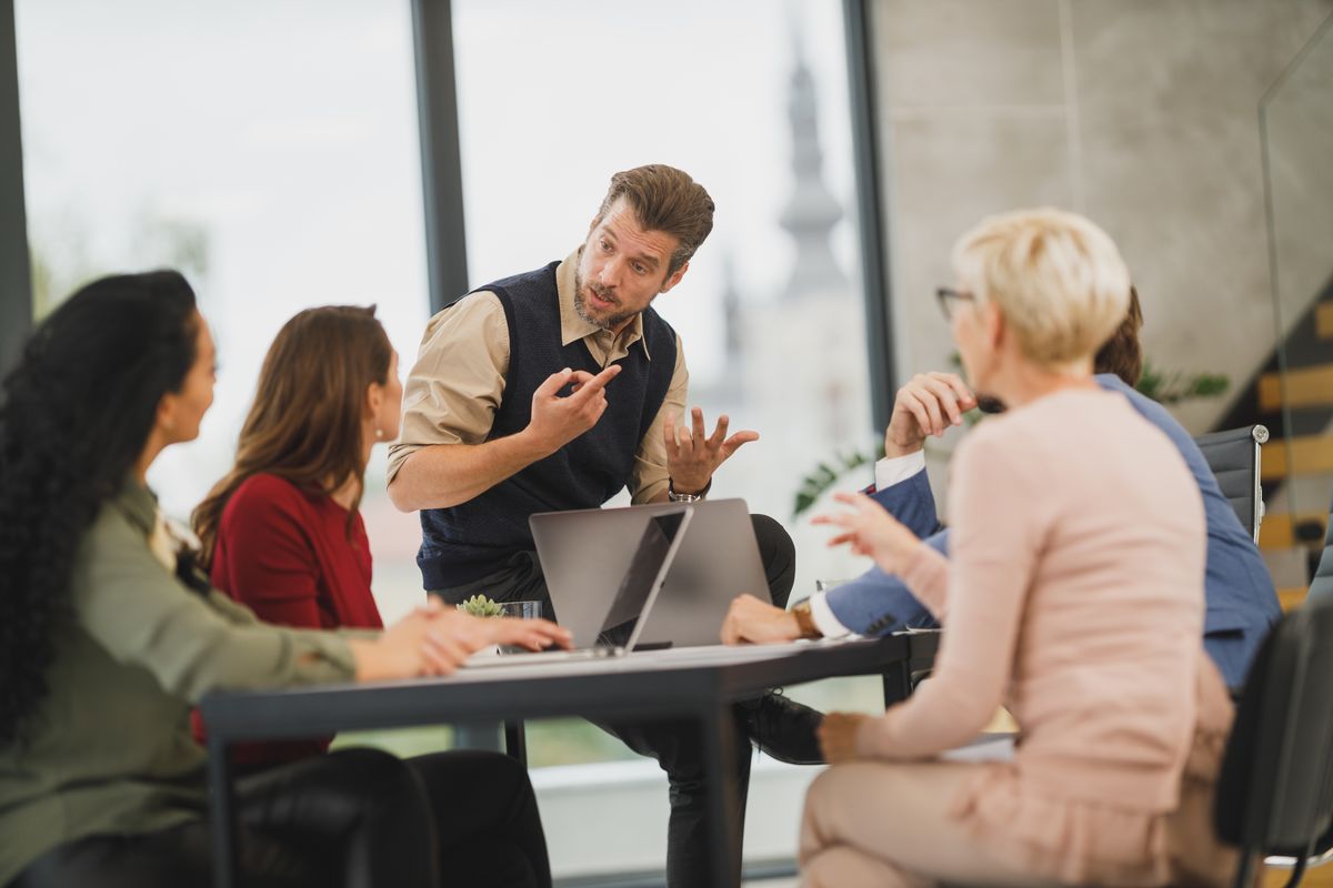 A team meeting around a conference table with laptops
